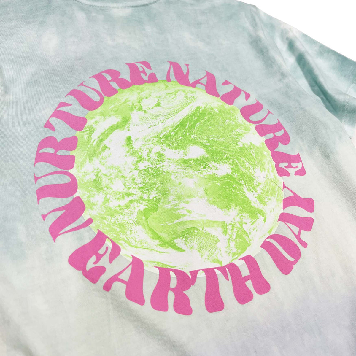 Nurture Nature pink text around on green earth graphic on the back of the shirt. Close up